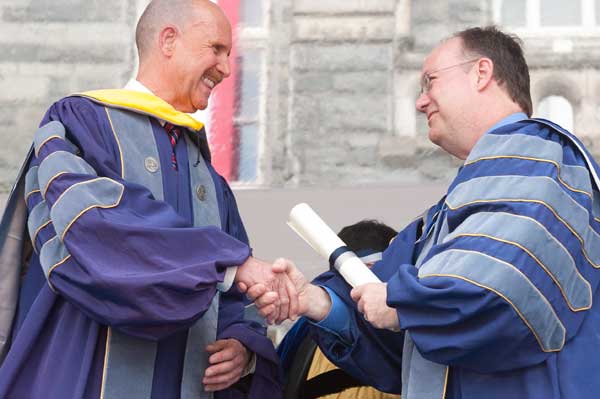 John Howard shakes hands with John J. DeGioia who is holding a scroll