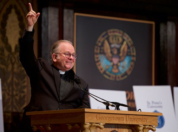 Rev. Patrick Conroy speaks at a lectern in Gaston Hall