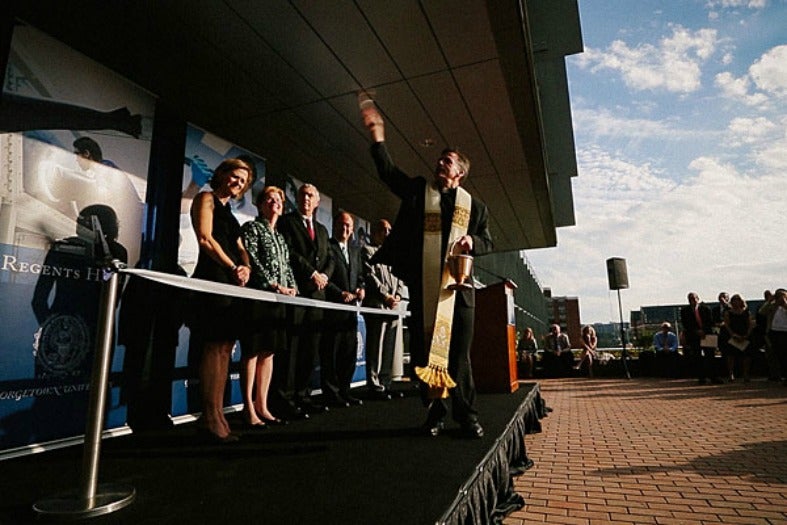 Kevin O'Brien turns to throw water on the building while others look on behind a ribbon