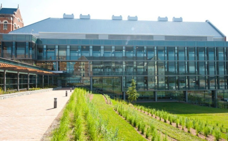 A view looks across a patio at the new Regents Hall with a grassy lawn below