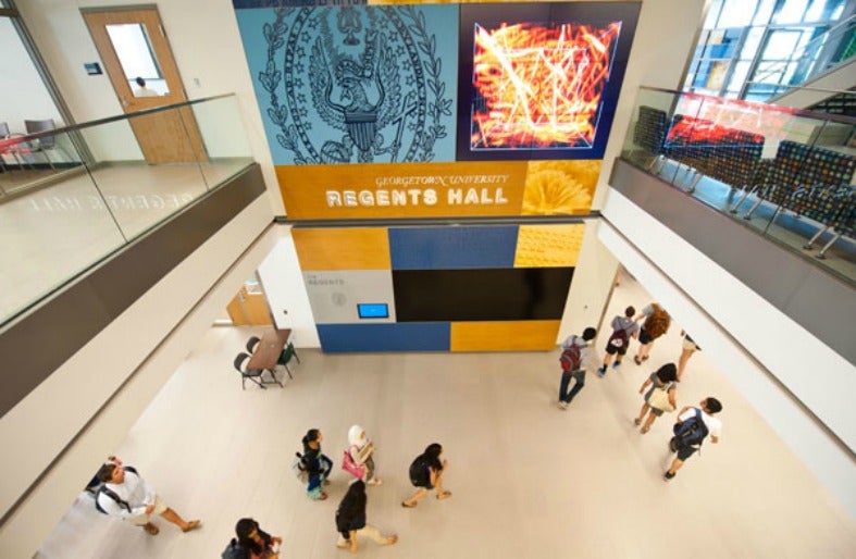 A view from an upper floor shows students walking past a sign for Regents Hall