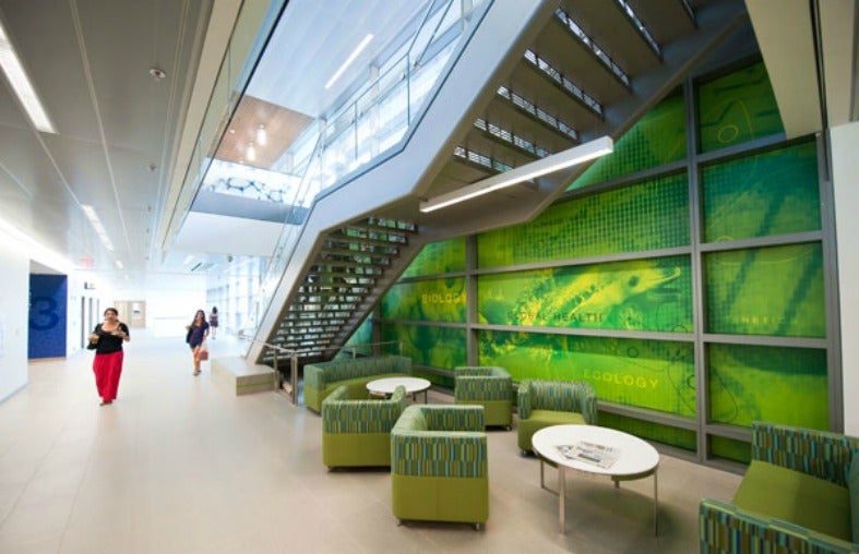 People walk past a staircase with furniture beneath it in Regents Hall