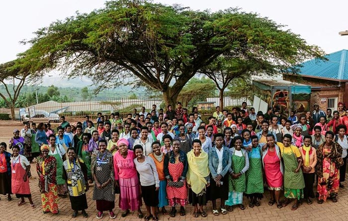 Workers gather and pose for a photo in front of a tree near their workplace