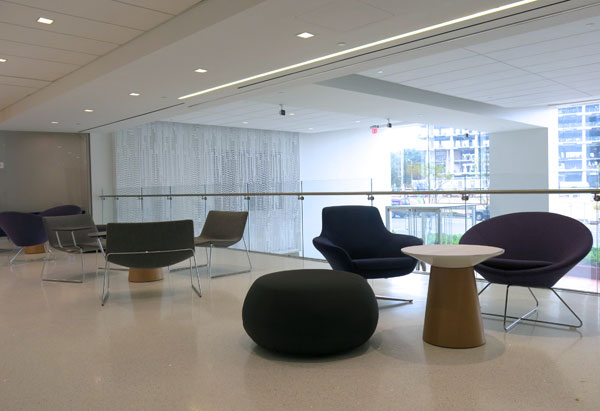 An open work space at SCS includes modern chairs and tables in front of glass walls that let natural light in to the lower level