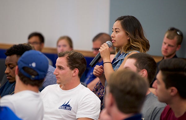A student stands to ask a question with a microphone during a teaching session