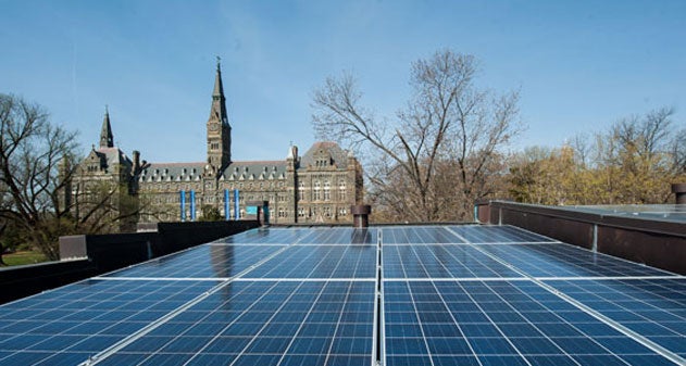 A photo of solar panels with Healy Hall in the background. 