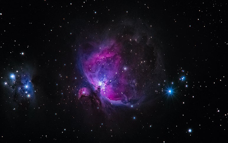 Image of purplish nebula emerging from pitch black outer space. 