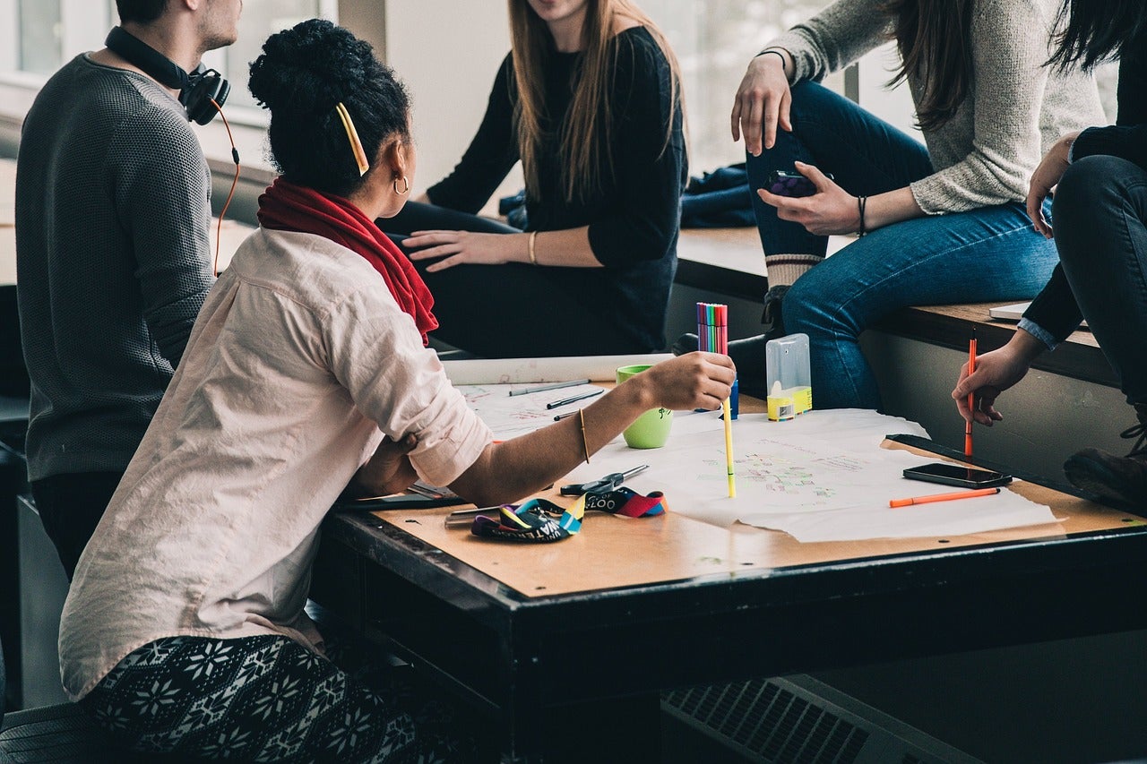 A group of people work on a project together at a desk