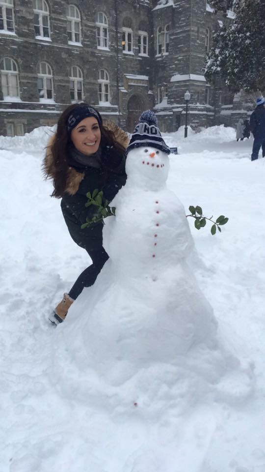A student builds a snowman on campus
