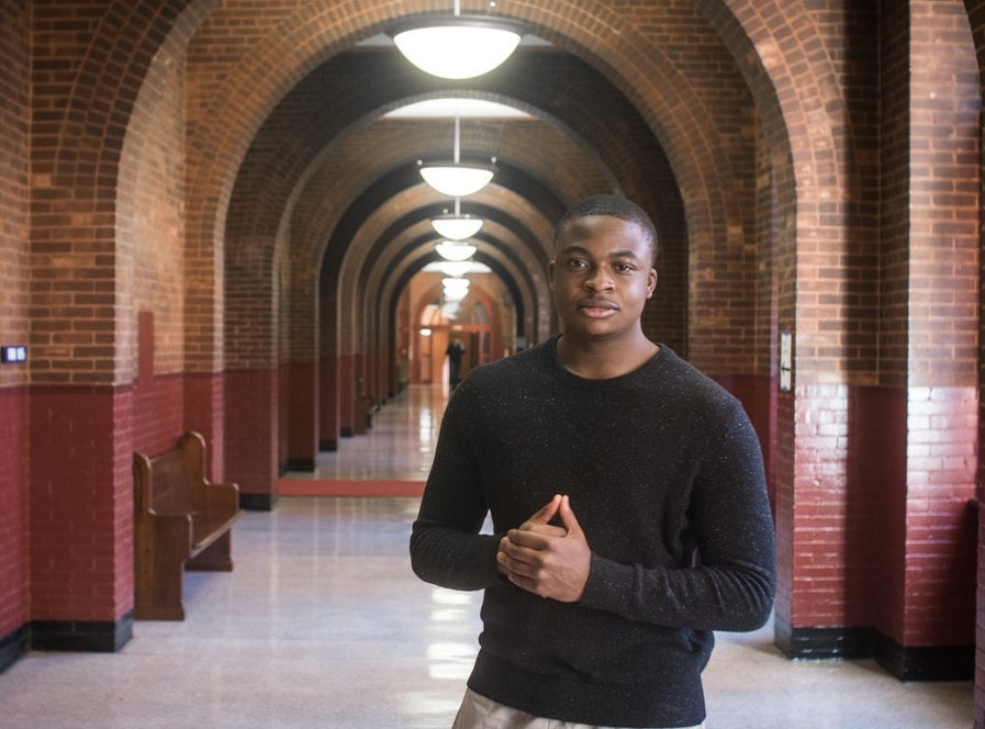 Ayodele Aruleba smiles for the camera in a hallway.