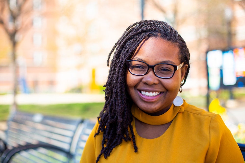 Toddchelle Young smiles for the camera on a campus bench.