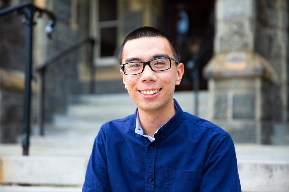 Jason Low smiles for the camera while sitting on steps. 