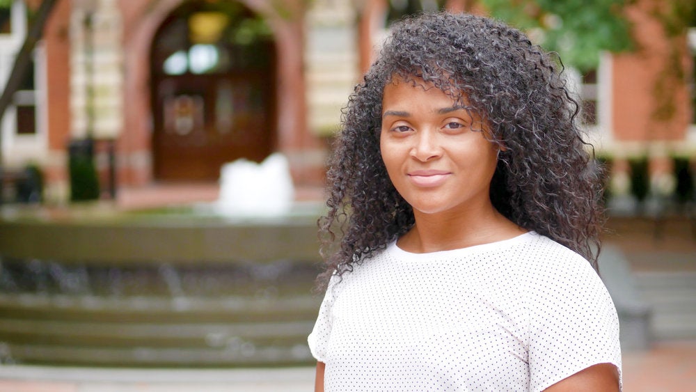 Jaime Brown smiles for the camera in front of a fountain. 