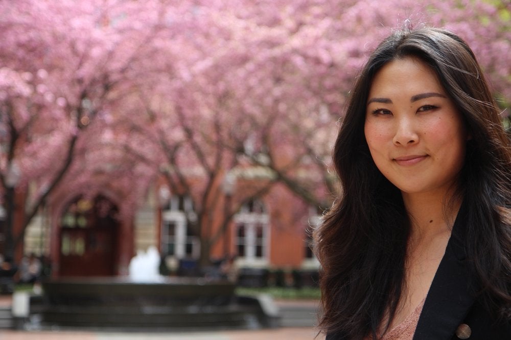 Jessica Lee smiles for the camera in front of a cherry blossom tree. 