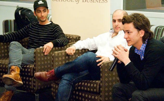 Nathaniel Ru speaks into a microphone while Jonathan Neman and Nicolas Jammet look on in Hariri Building