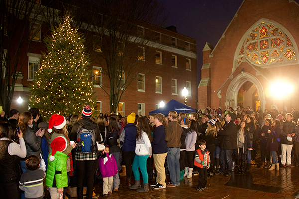 People gather outside in Dahlgren Quad next to a lit Christmas Tree with Dahlgren Chapel to the back right