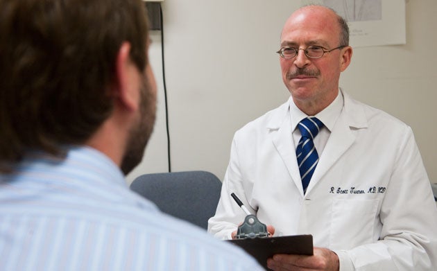 Dr. Scott Turner takes notes on a clipboard while listening to a man 