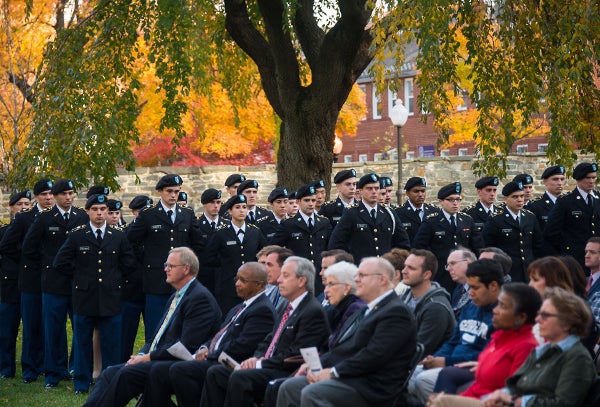 Georgetown community members sit on Copley Lawn and watch a procession of uniformed service members walk-by.