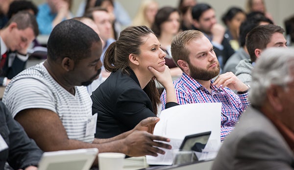 Students listen to a speaker in a classroom.