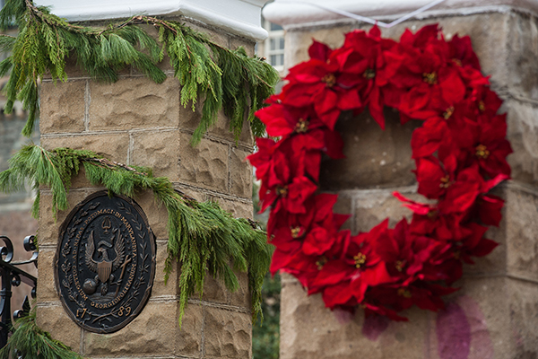 A red wreath hangs on one pillar while the Georgetown seal is on another at the front gates 